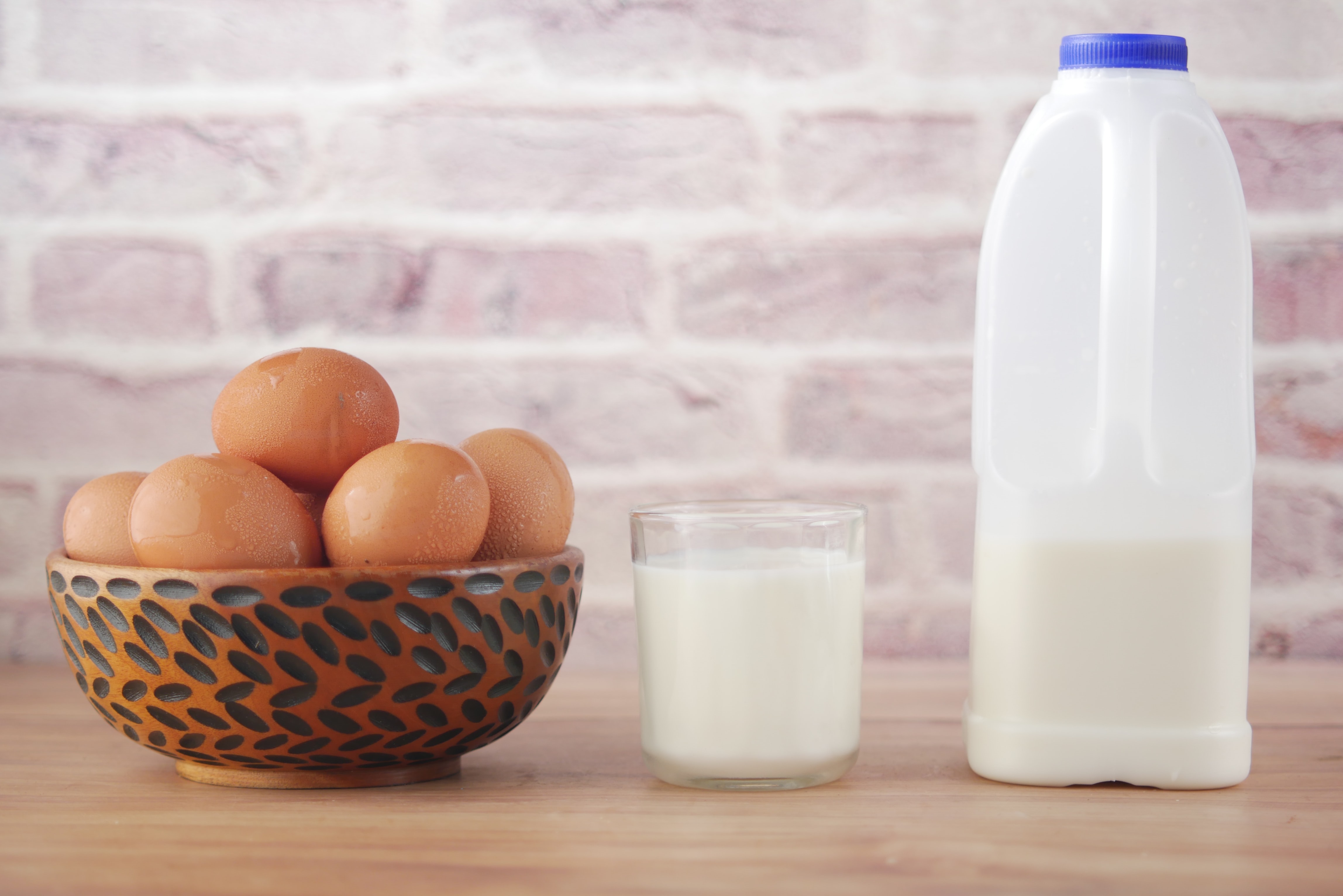 A glass cup with milk and a bowl of eggs