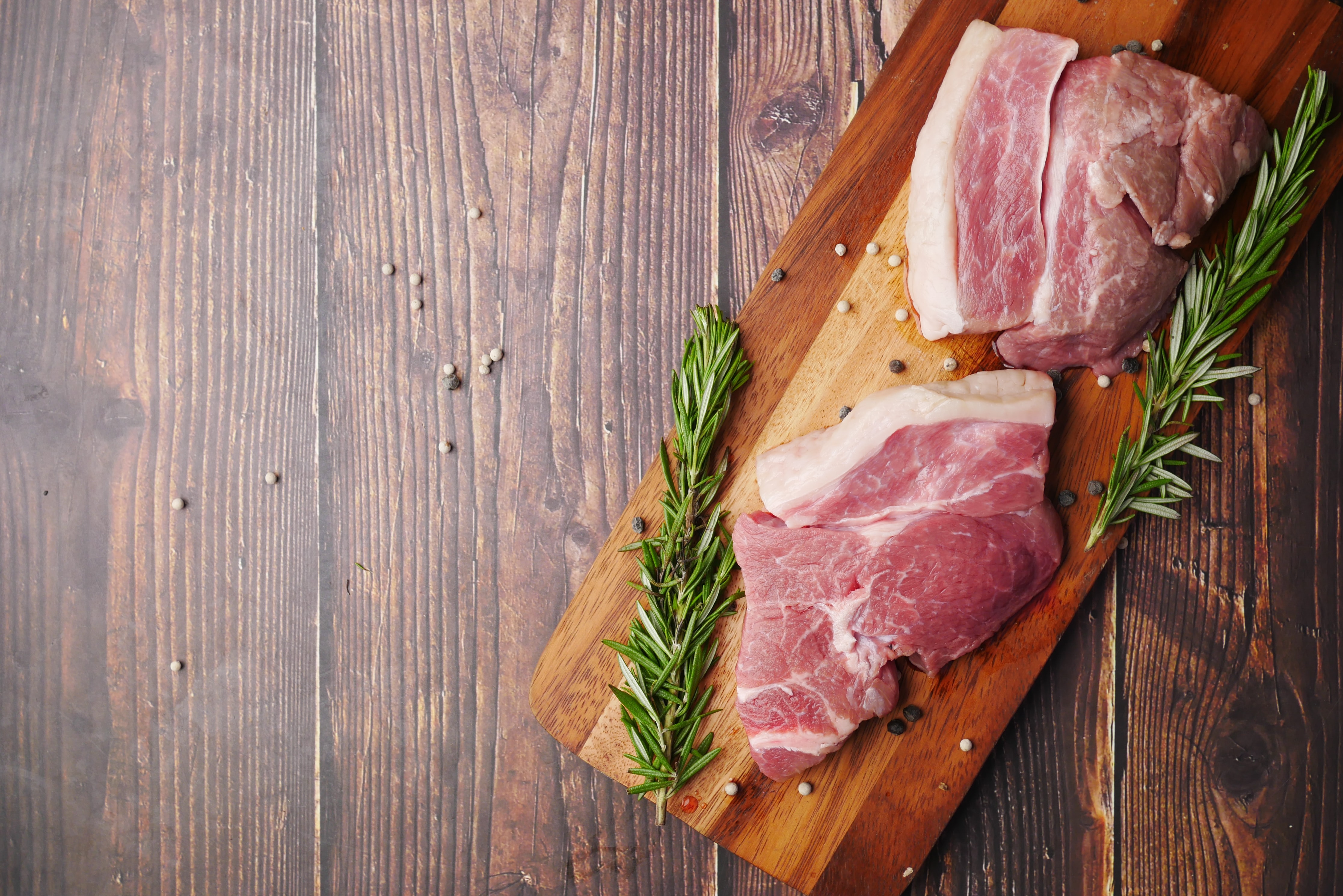 Steak resting on a cutting board with rosemary